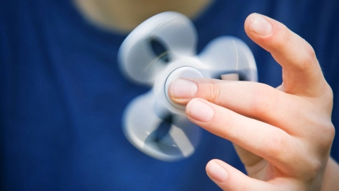 Fingers twirling a fidget spinner.