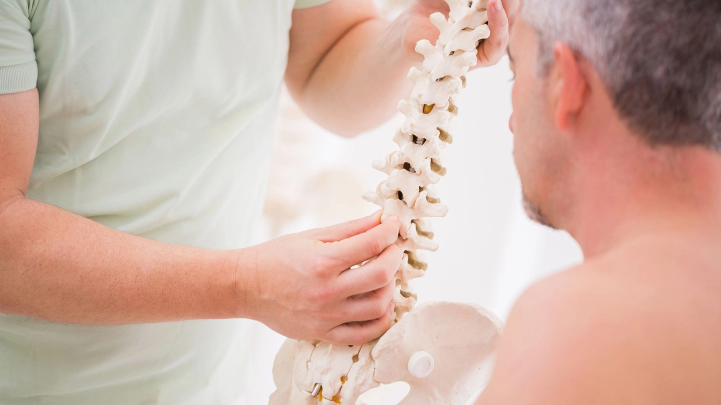Disk kayması (Kaynak: Getty Images/DianaHirsch) Bir doktor bir erkeğe bir omurga modeli gösteriyor.