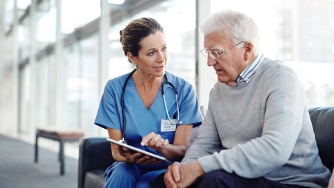 A doctor uses a tablet to explain something to a man.