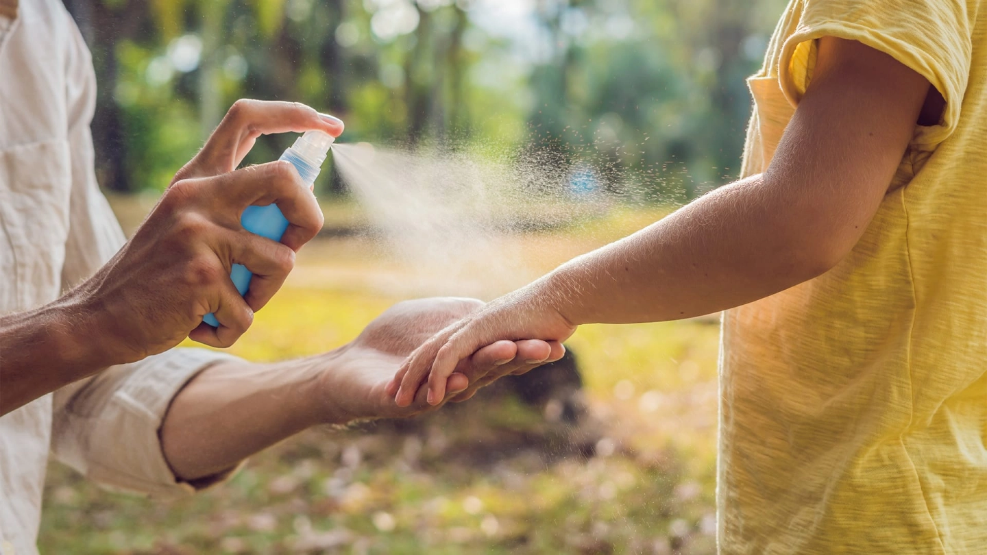 الأمراض المعدية الغريبة (المصدر: iStock/galitskaya) الأمراض المعدية الغريبة: لقطة مقربة لأيدي وأذرع لقميصين يرتديهما بعض الأشخاص، أمام خلفية تشبه الحديقة. شخص يحمل ذراع شخص آخر، ويرش رذاذ الحماية من البعوض عليها.