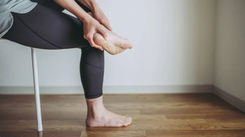 Otururken topuklarını tutan bir kişi