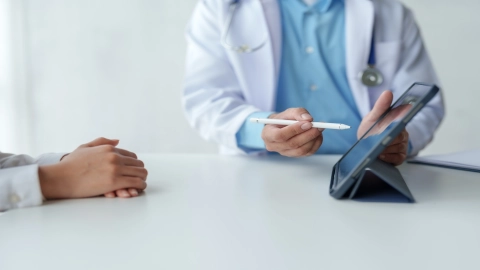 Ein Arzt zeigt einer Patientin oder einem Patienten etwas am Tablet.