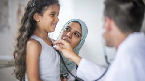 Ein Arzt hört ein kleines Mädchen mit dem Stethoskop ab