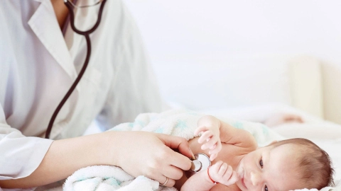 Doktor bir bebeğin kalbini steteskopla dinliyor.