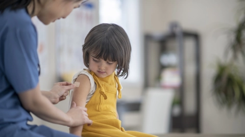 Vaccinations: a doctor holding a drawn syringe in his hand in front of a patient