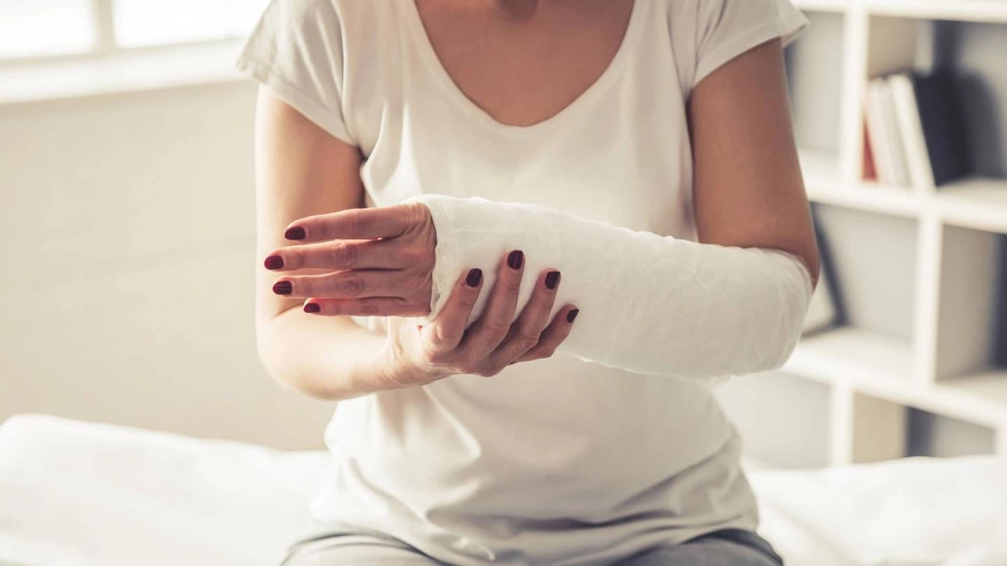 Kompartmentsyndrom (Quelle: iStock/vadimguzhva) Nahaufnahme einer Frau mit geschientem Unterarm, die auf einer Behandlungsliege sitzt.