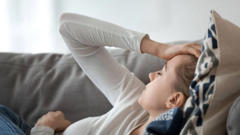 A young woman lies exhausted on the couch.
