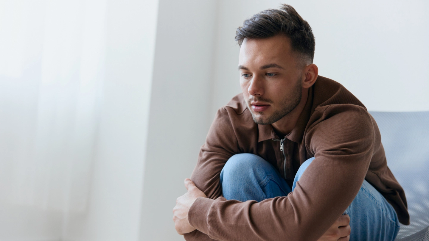 Mit Angst umgehen (Quelle: iStock/EyeEm Mobile GmbH) Eine junger Mann sitzt vorgebeugt auf einem Stuhl und hat die Arme um seine Knie geschlungen.