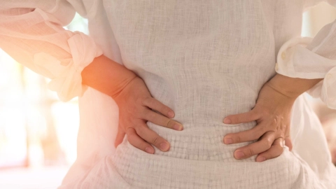 A woman with her hands holding on her sides and bending her body backwards slightly.
