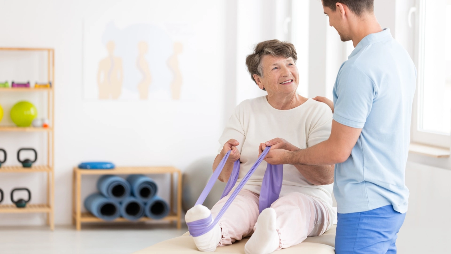 Osteoporose (Quelle: Getty Images/KatarzynaBialasiewicz) Eine ältere Frau trainiert unter Anleitung mit einem Fitnessband