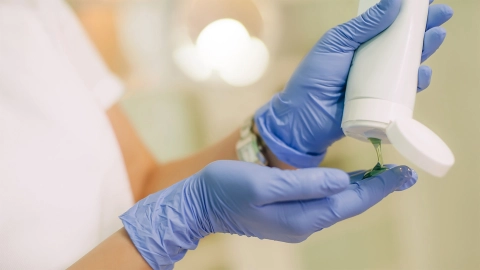 Tek kullanımlık eldiven giymiş bir kadın jel uyguluyor.