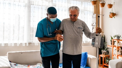 A health visitor assists a senior citizen during a home visit.