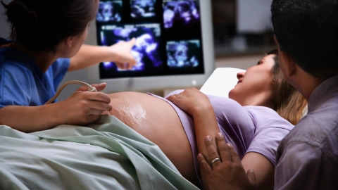 Ultrason muayenesinde yanında kocası ve doktoruyla gebe bir kadın.