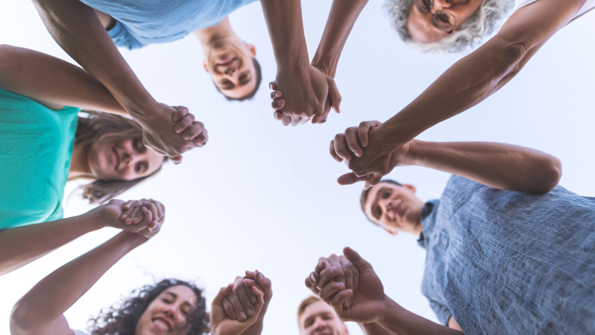 Menschen stehen im Kreis und halten sich an den Händen.