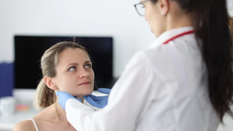 Врач пальпирует пациента в области подчелюстной железы.