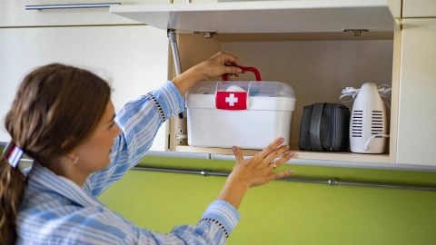 A woman putting a first-aid box with medication into a refrigerator