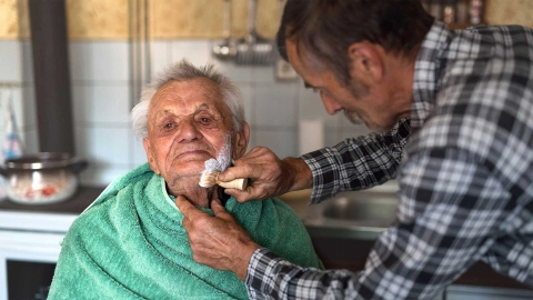 رجل مسن يحلق ذقنه.