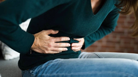 Женщина обеими руками держится за живот.